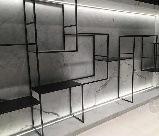 Blackened steel geometric shelving on a backlit marble wall