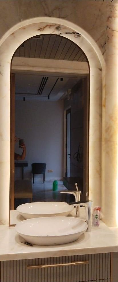 Brass arched mirror above a fluted vanity
