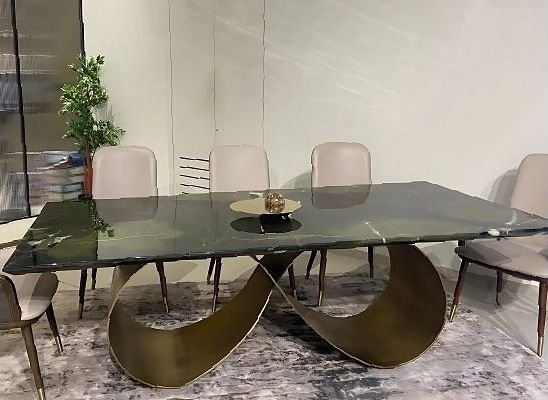 Dining table on a sculpted brass base with a glass top