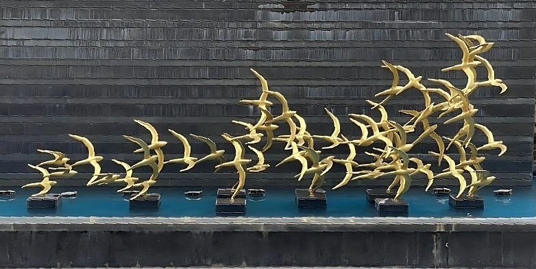 Flock of brass birds mounted as an exterior sculpture