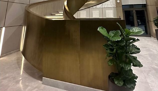 Curved brass staircase and reception counter in a hotel lobby