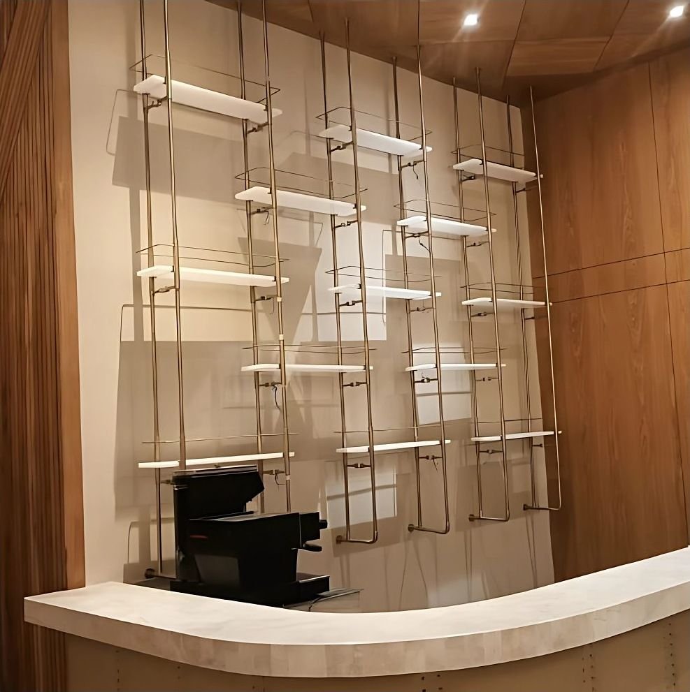 Slender brass display shelving against a marble wall