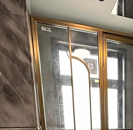 Brass-framed arched shower screen against marble