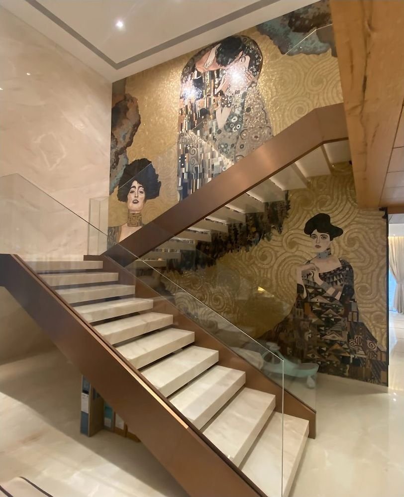 Brass and glass staircase in a hotel lobby with a mural wall