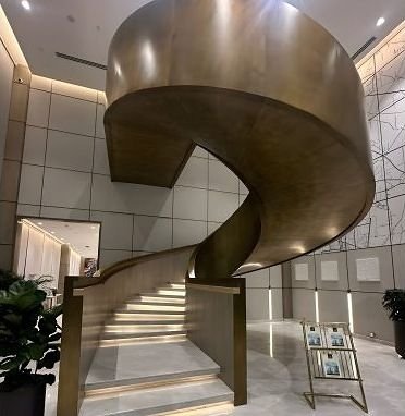Bespoke bronze spiral staircase rising through a double-height lobby