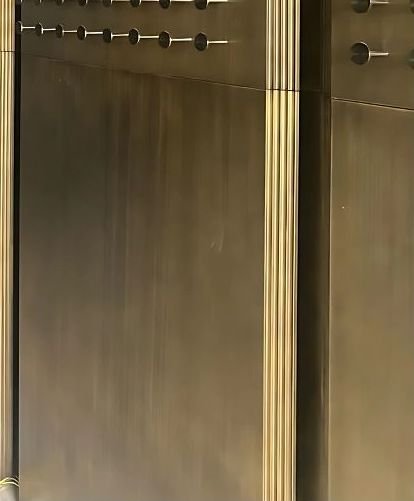 Brushed brass wall cladding in a lift lobby