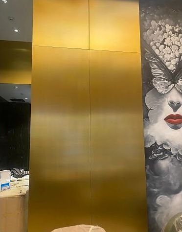 Brushed gold metal wall panel beside printed art