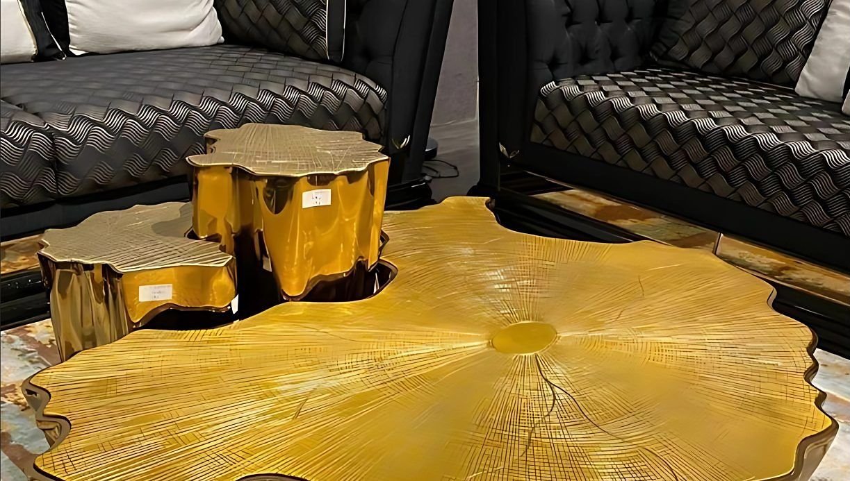 Sculptural gold-finished centre table between tufted sofas
