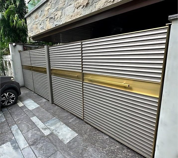 Louvred metal boundary gate with a brass band