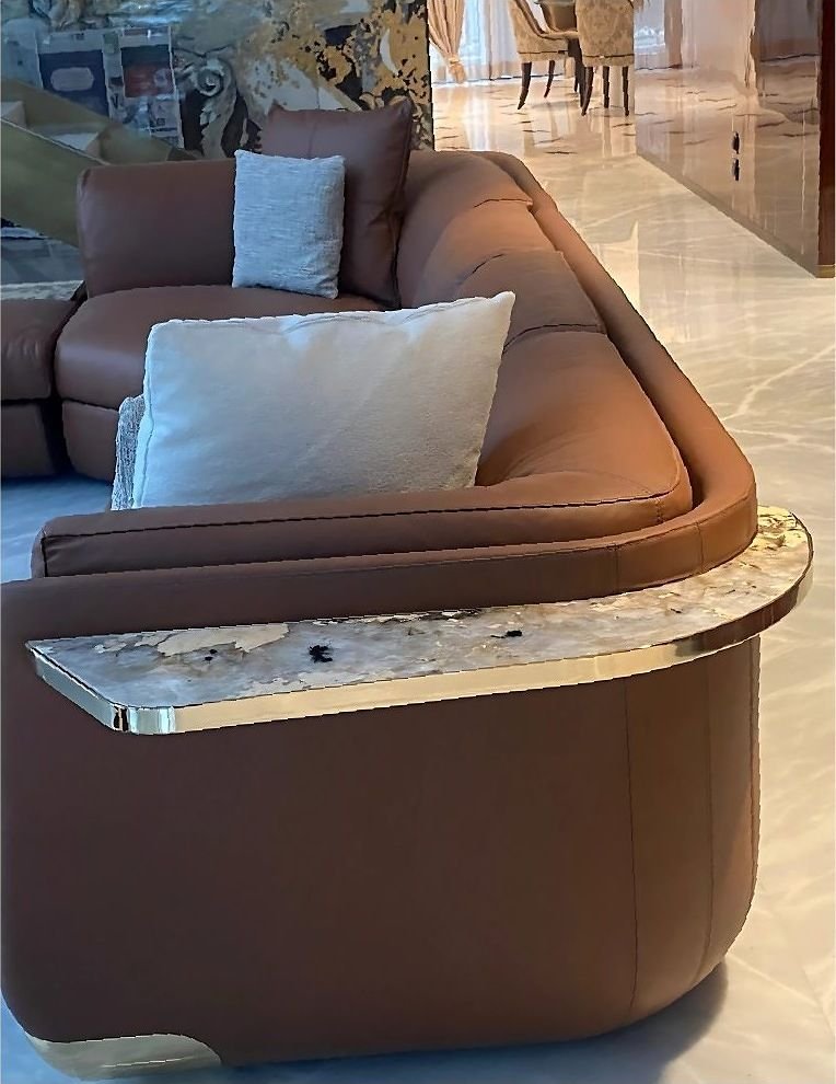 Metal-edged side table with a stone top beside a leather sofa