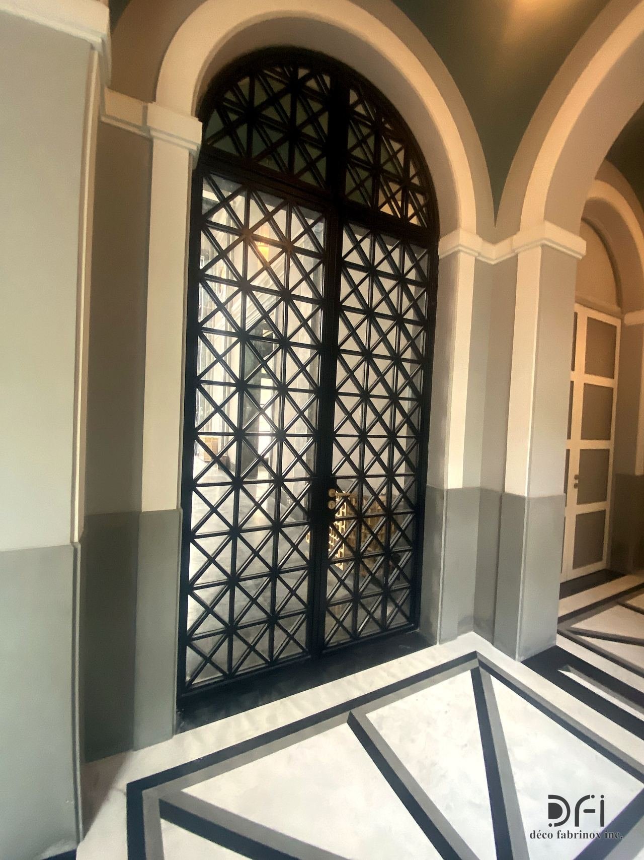 Arched black metal lattice double door in a classical hall