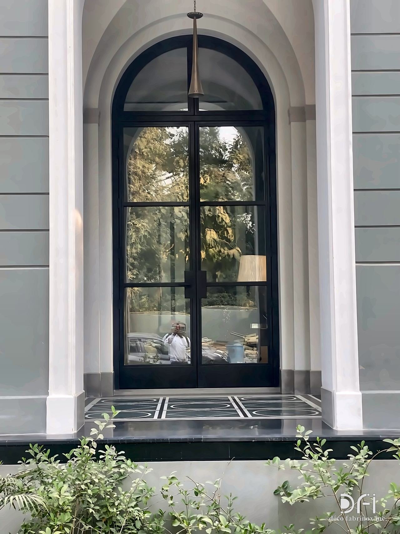 Arched black steel-framed glass entrance door