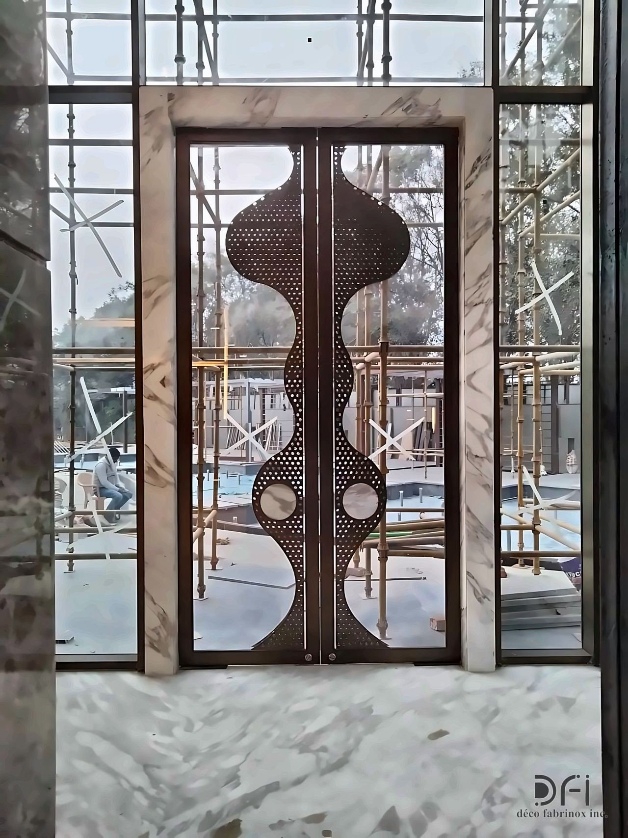 Bronze entrance door with a sculpted perforated centre