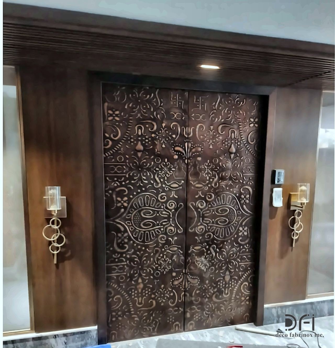 Embossed bronze entrance doors with brass wall lights