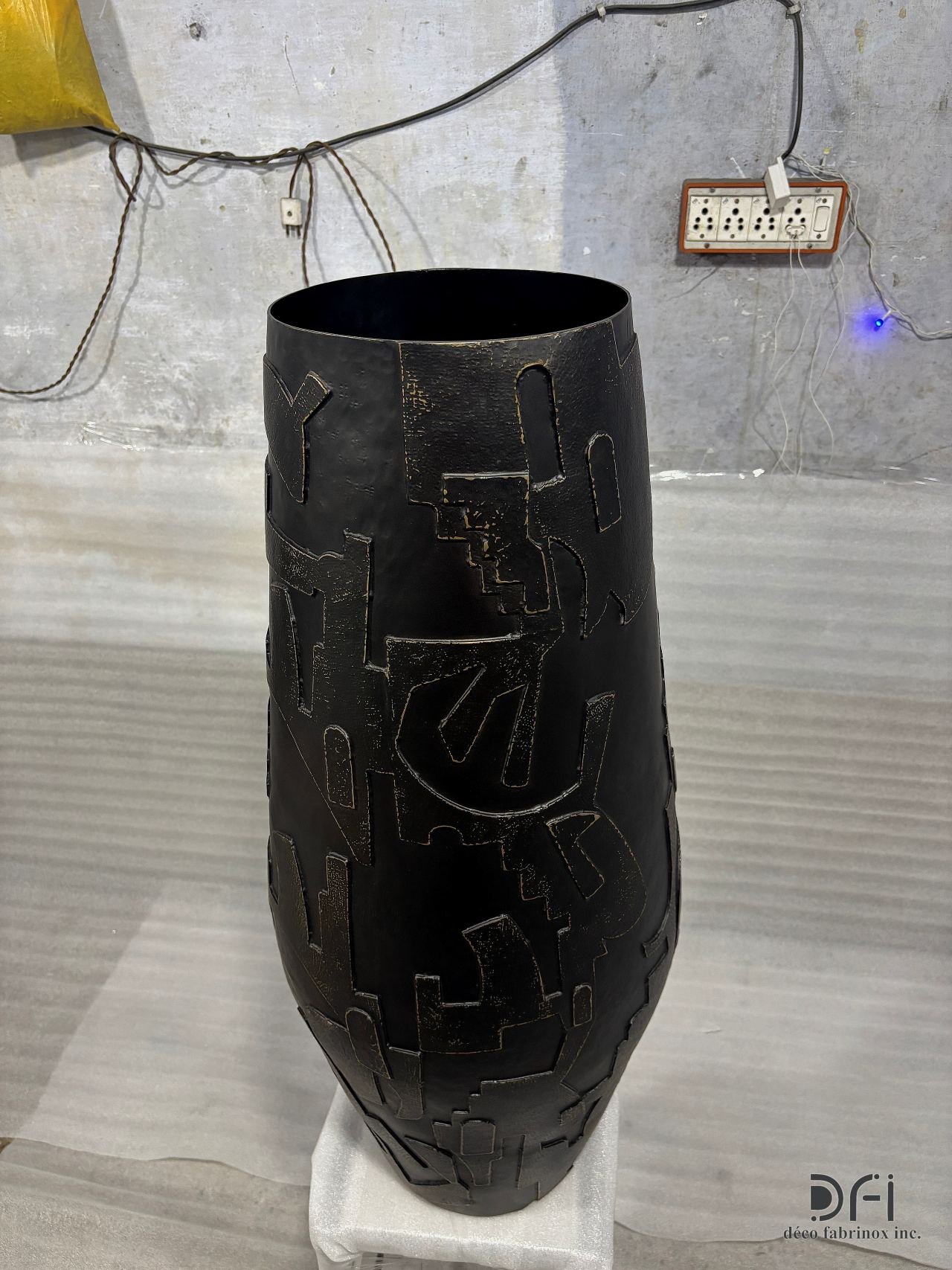 Tall black metal vase with a gold relief pattern