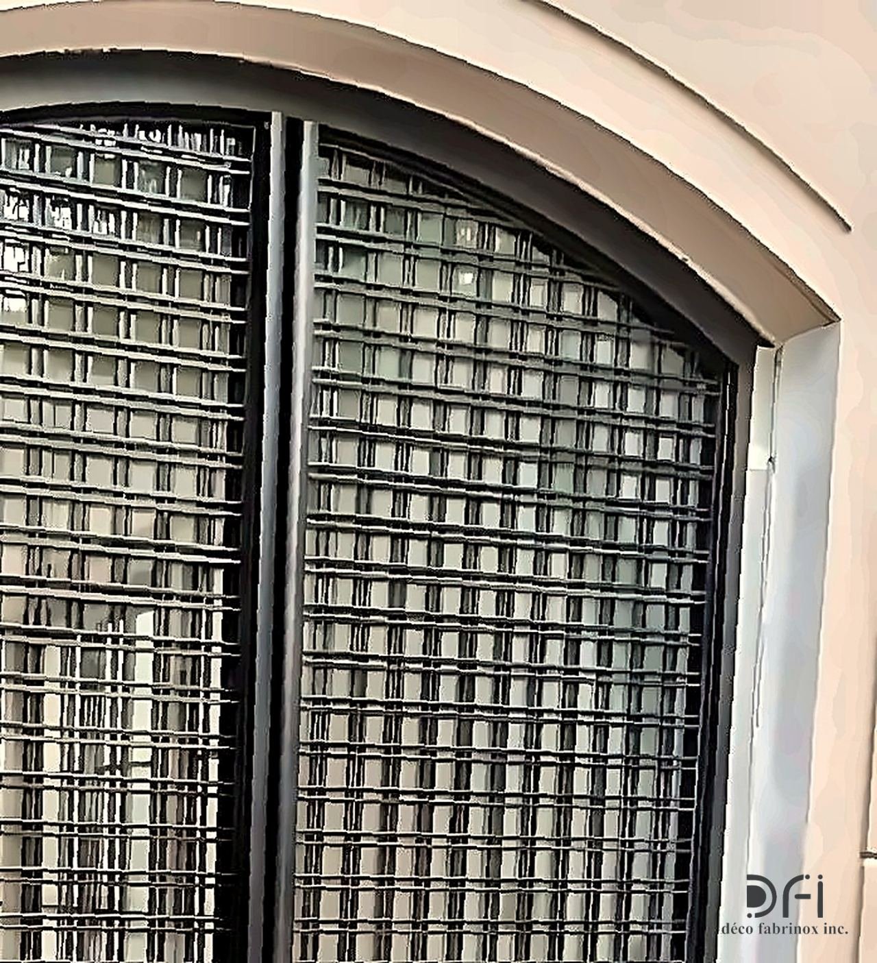 Blackened steel screen over an arched facade window