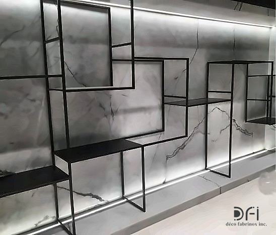 Blackened steel geometric shelving on a backlit marble wall