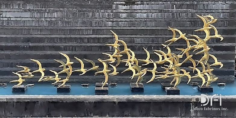 Flock of brass birds mounted as an exterior sculpture