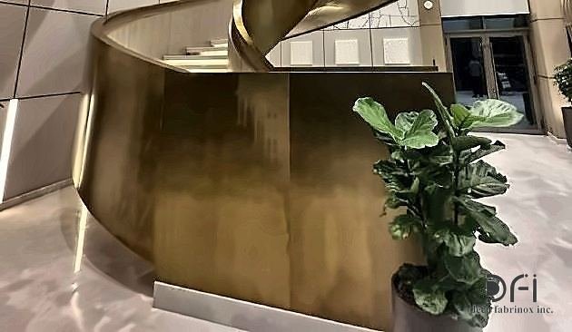 Curved brass staircase and reception counter in a hotel lobby