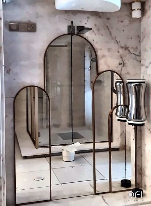 Brass-framed arched mirror panels in a marble bathroom