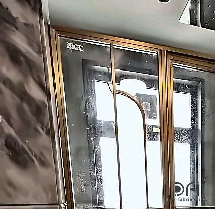 Brass-framed arched shower screen against marble