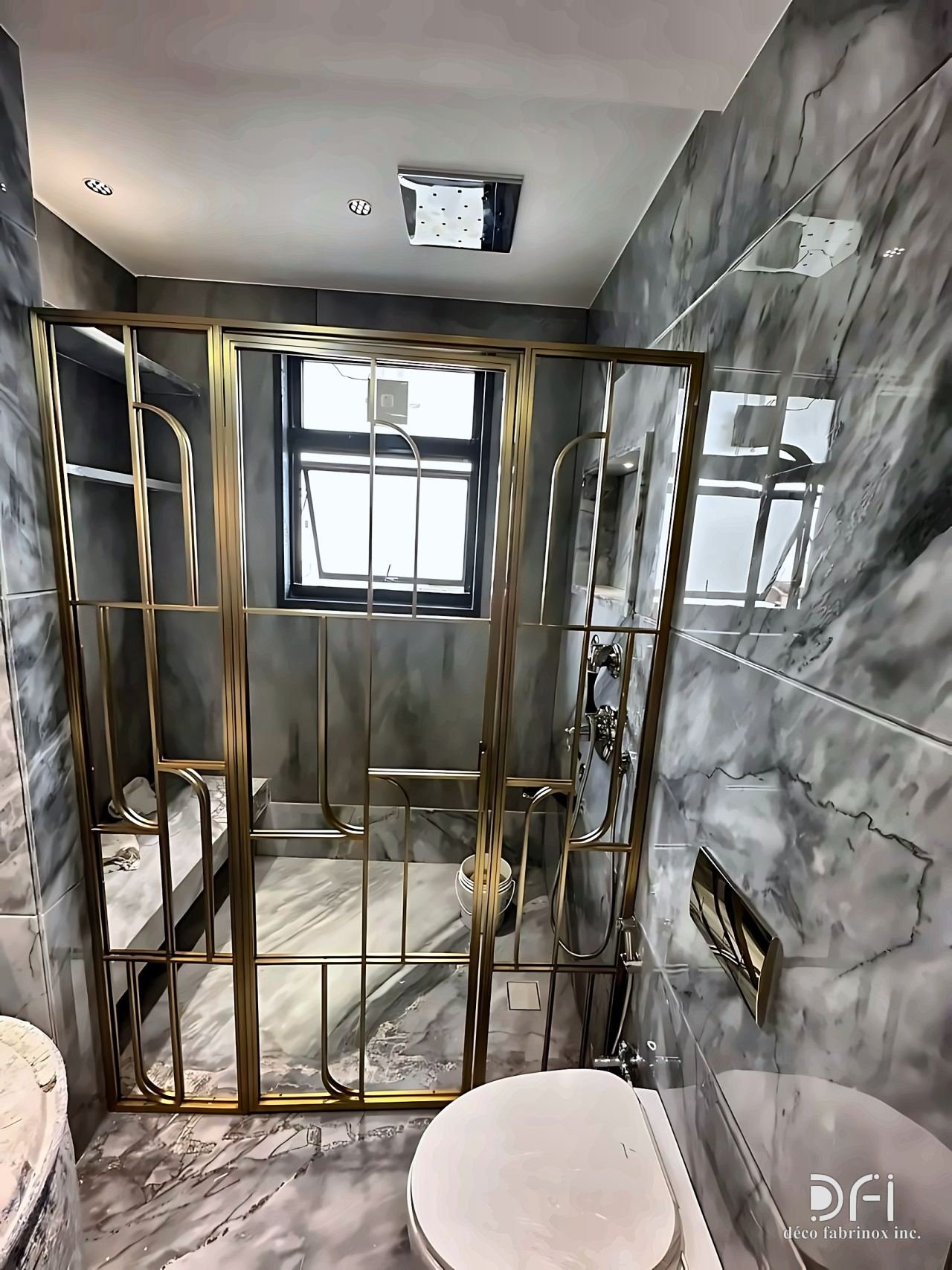 Brass-framed shower enclosure with grid glazing in a grey marble bathroom