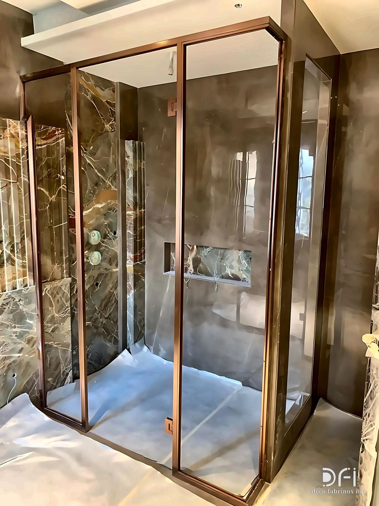 Copper-toned framed shower enclosure on marble