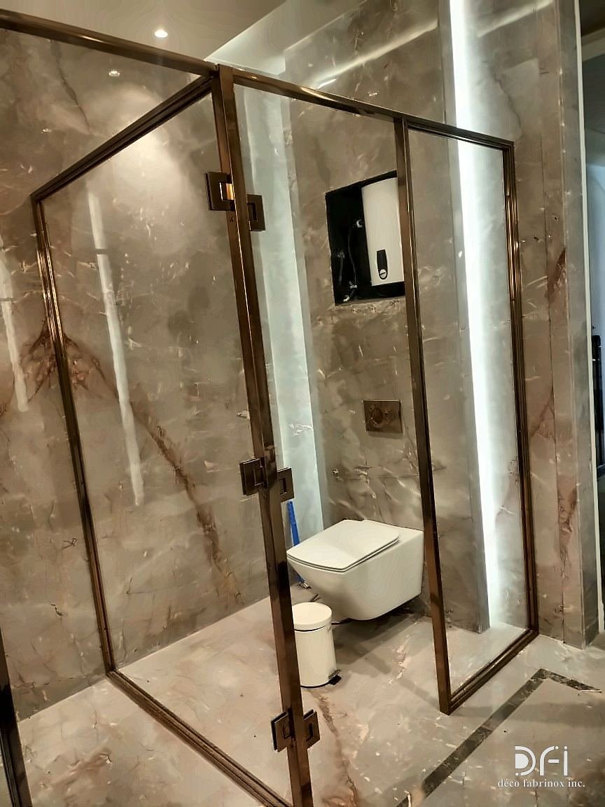 Bronze-framed glass shower enclosure beside a wall-hung toilet