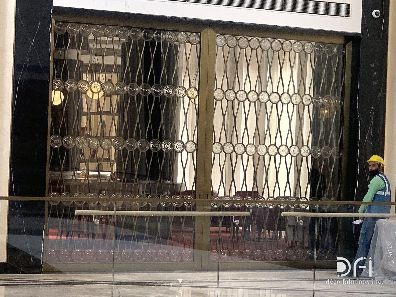 Brass oval-lattice glazed screen at a building entrance