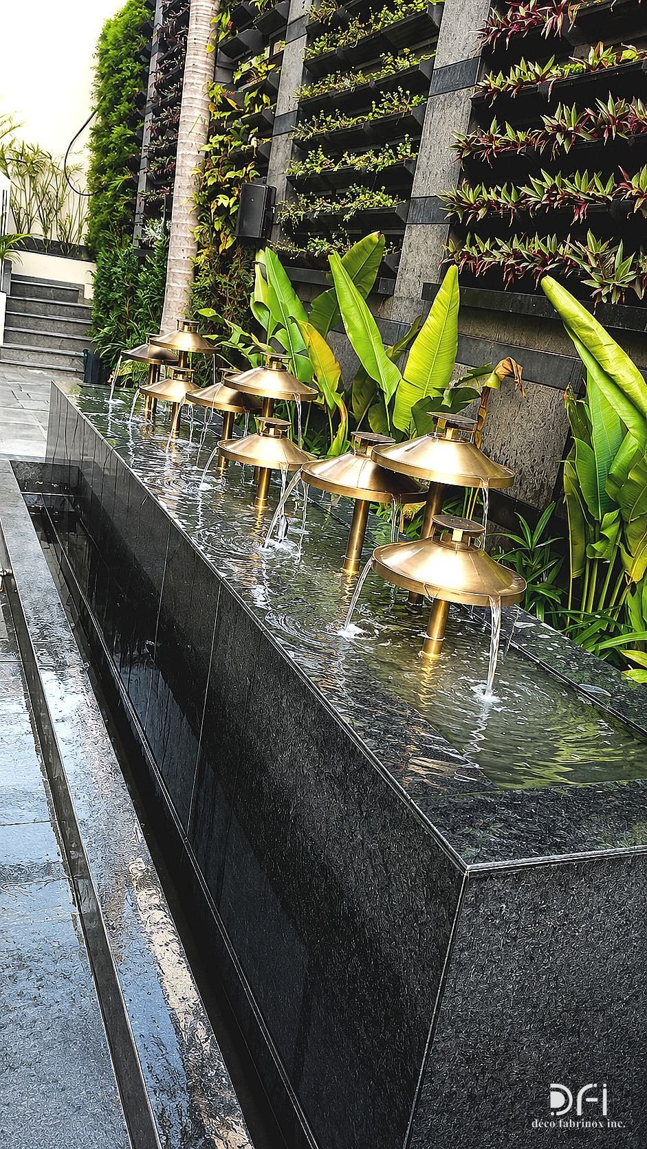 Brass bowl water feature along a black granite trough