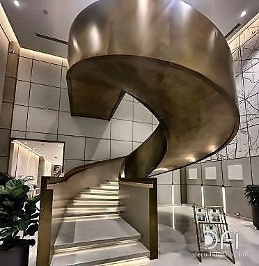 Bespoke bronze spiral staircase rising through a double-height lobby