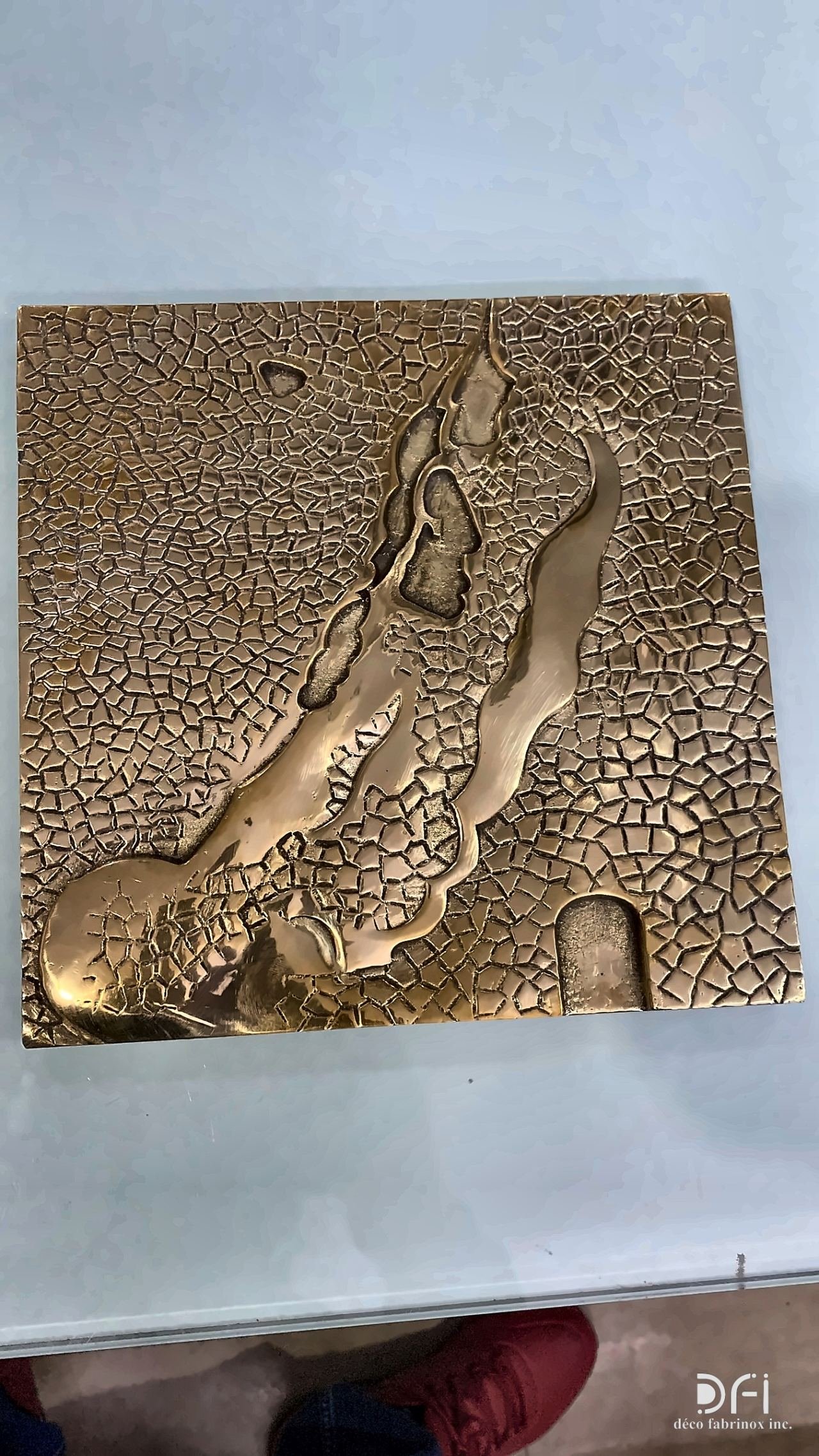 Cast bronze relief with a river-and-stone pattern