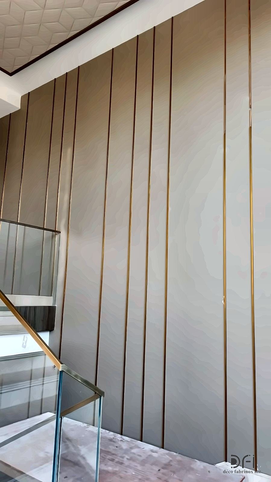 Thin brass inlay strips set into wall panels beside a glass balustrade