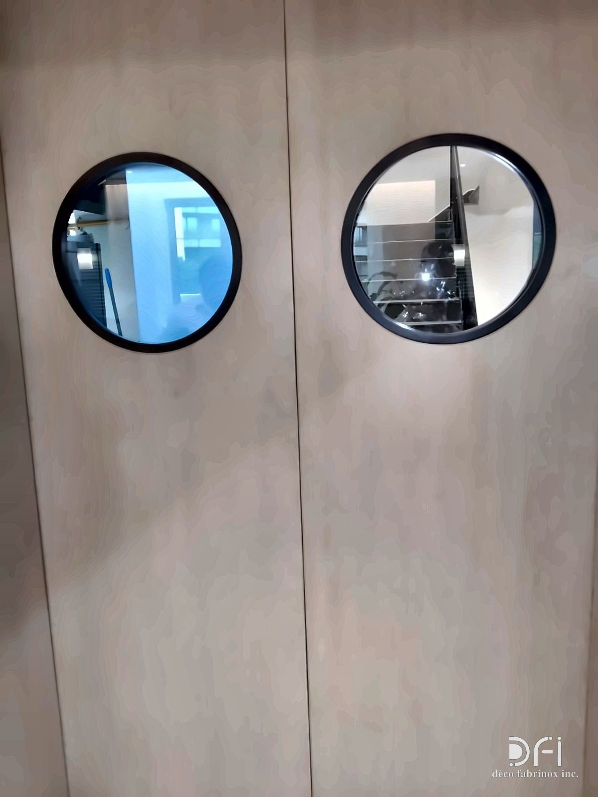 Round dark metal porthole frames set into a pair of veneered doors