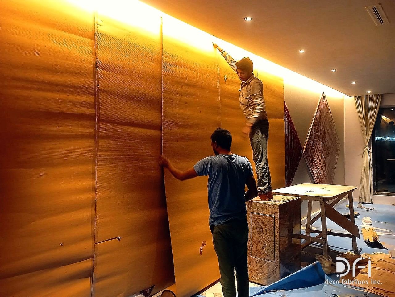 DFI team installing copper-finish wall panels in a hotel corridor
