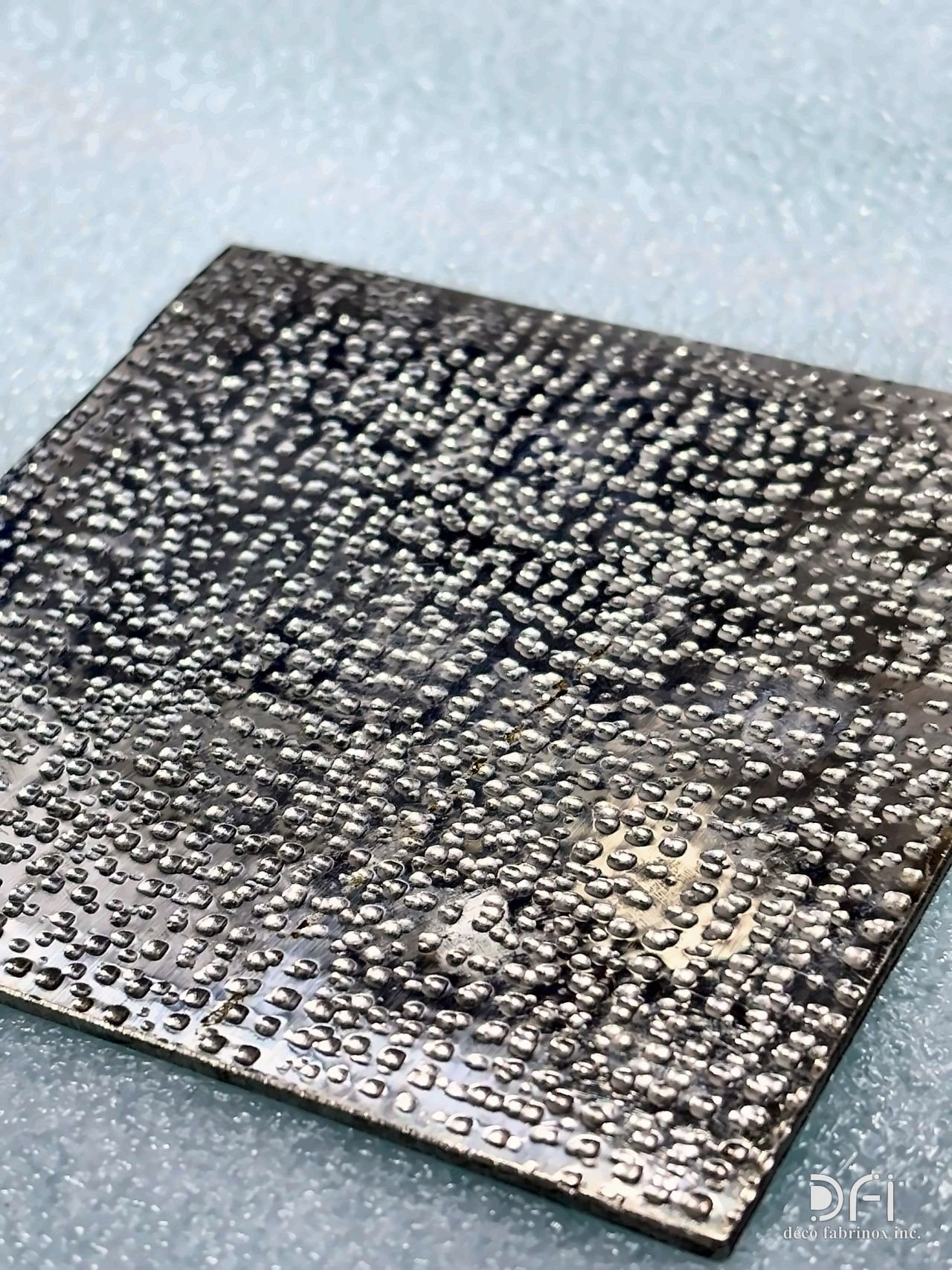 Embossed dotted texture on a blackened metal sample