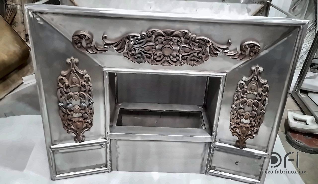 Silver-finished fireplace front with copper-toned ornament, in the workshop
