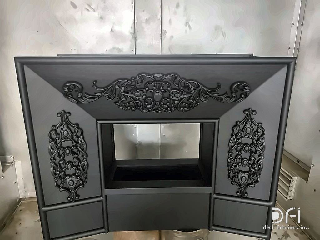 Black fireplace front with ornamental cast panels, in the workshop