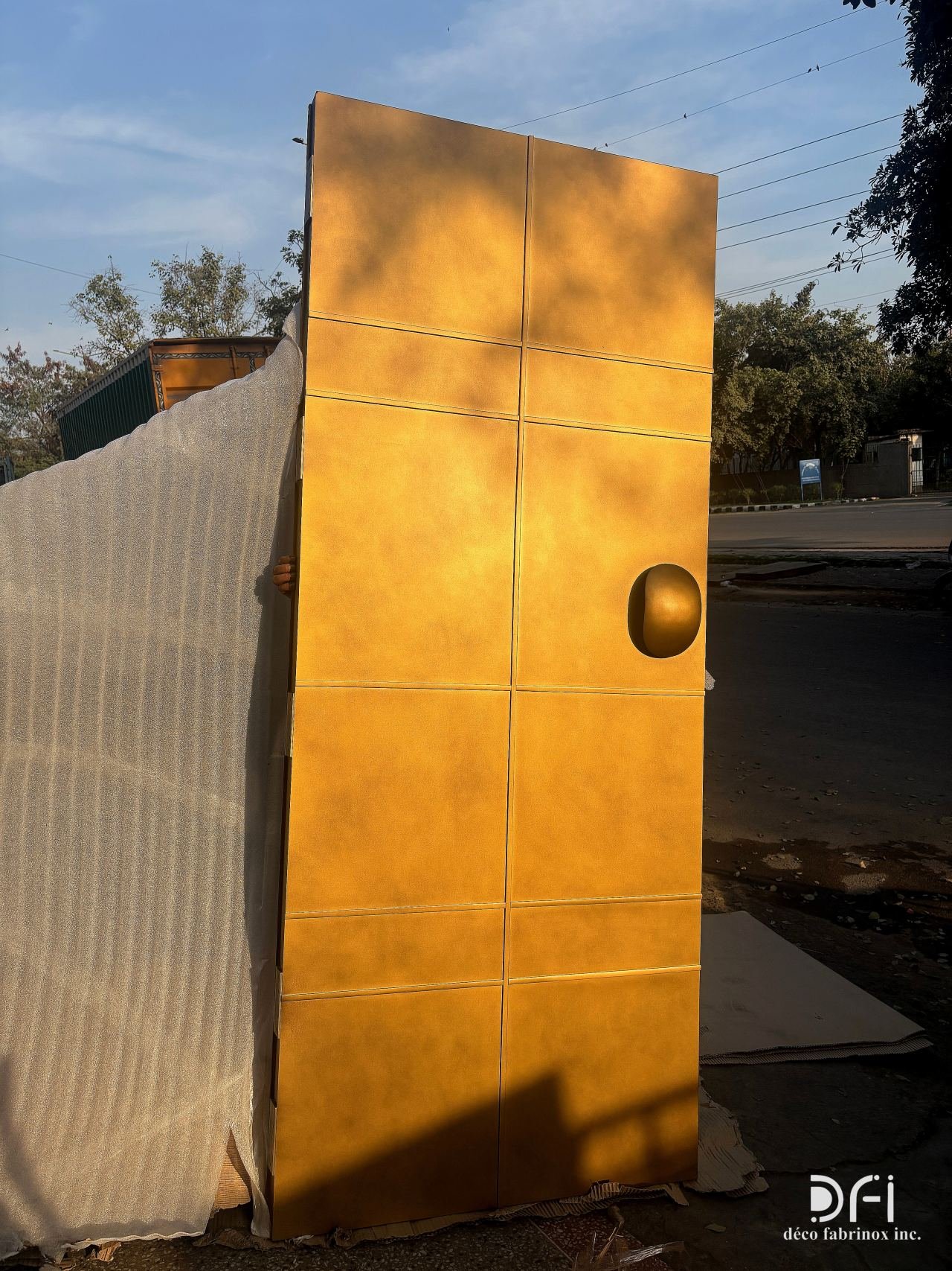 Finished gold door panel with a pebble handle in daylight