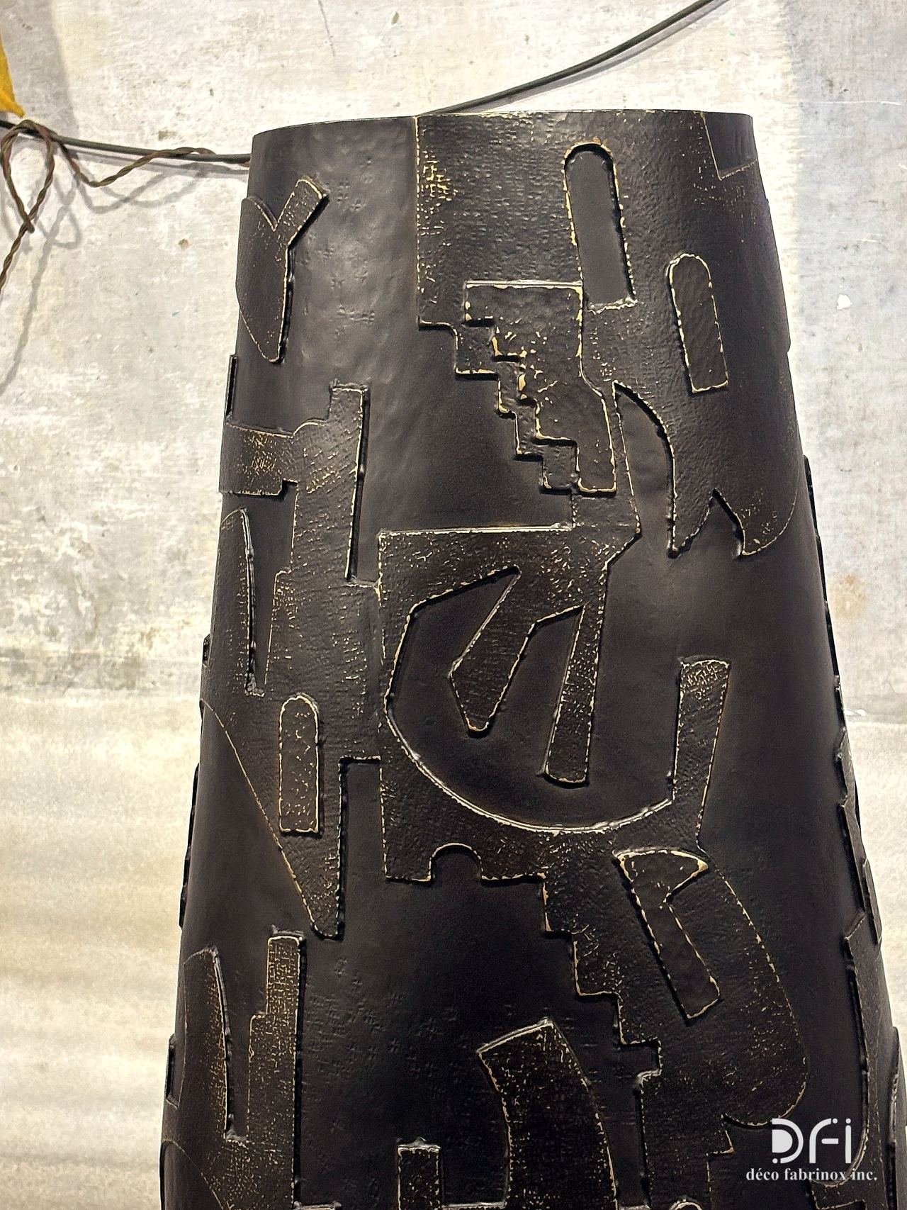 Hand-welded relief pattern on a black metal vase, close view