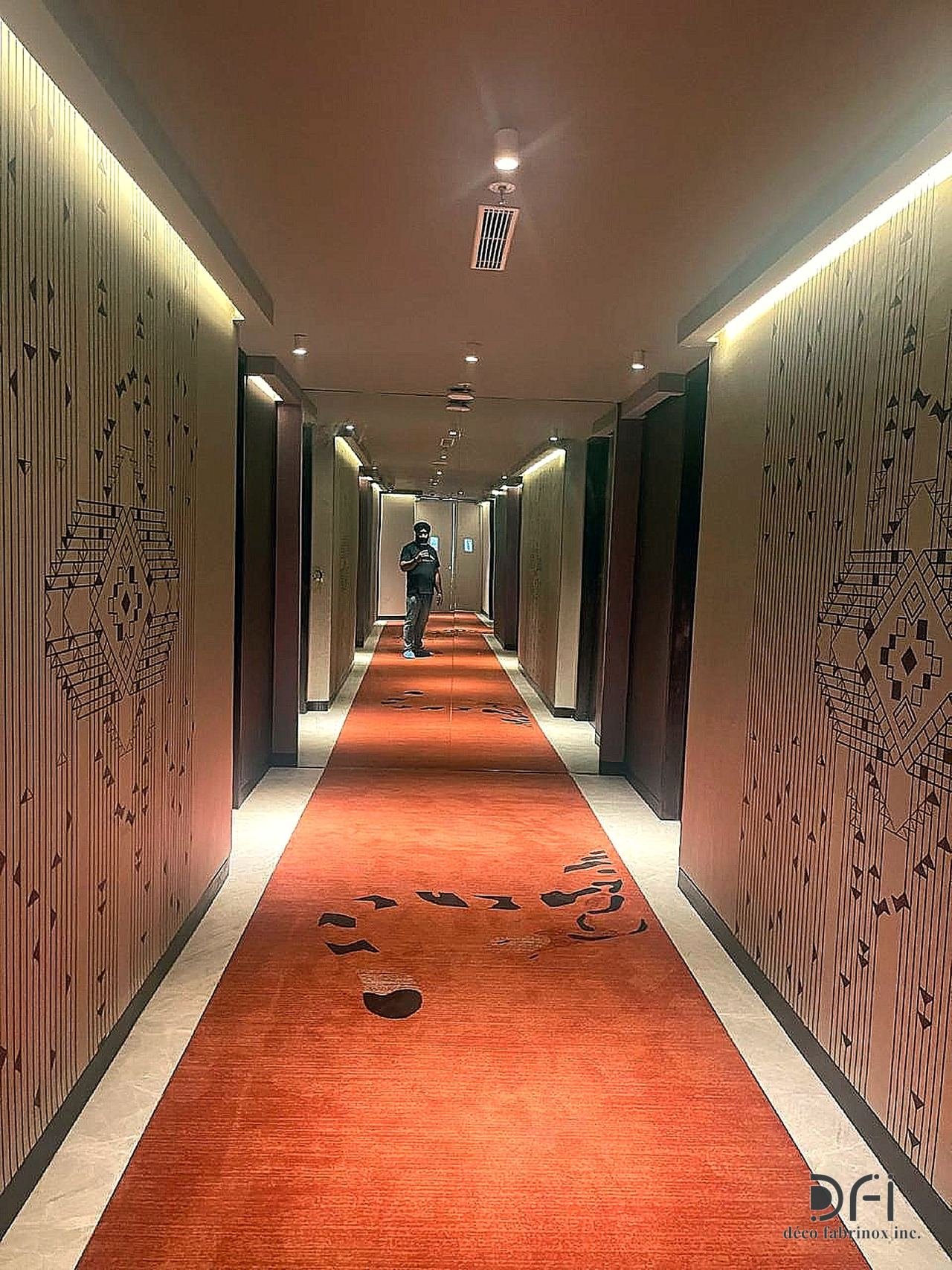 Hotel corridor lined with laser-cut metal wall panels