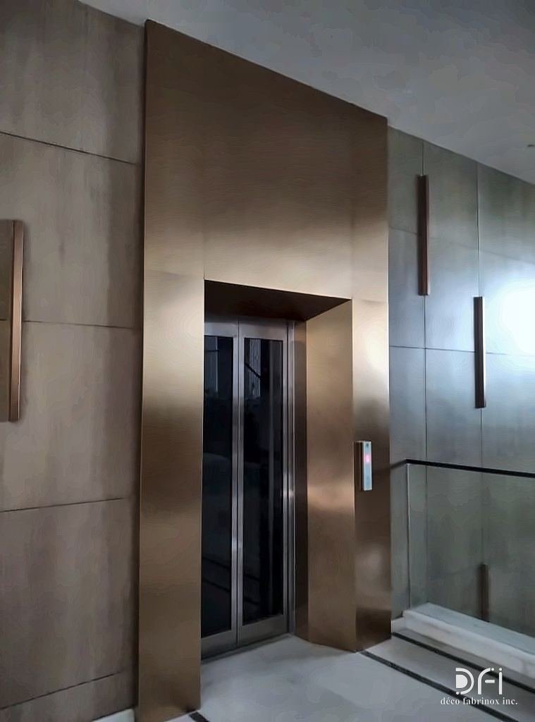 Lift entrance with a warm metal portal frame and matching side panels