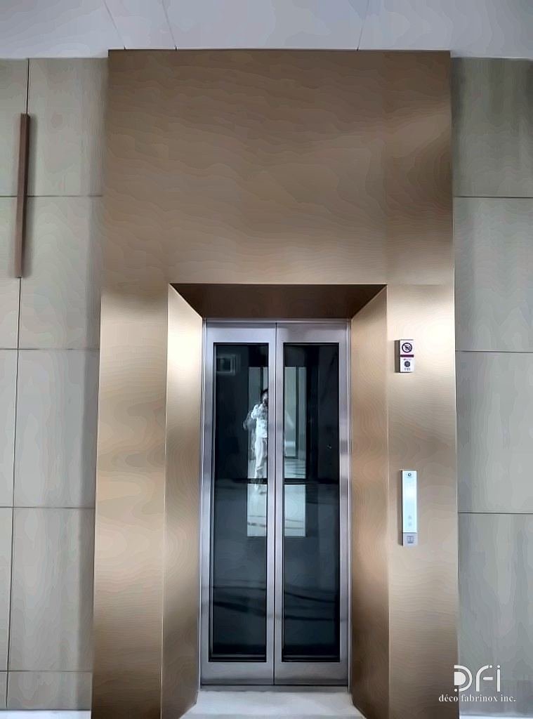 Warm-toned metal lift portal with a recessed frame in a stone-clad wall