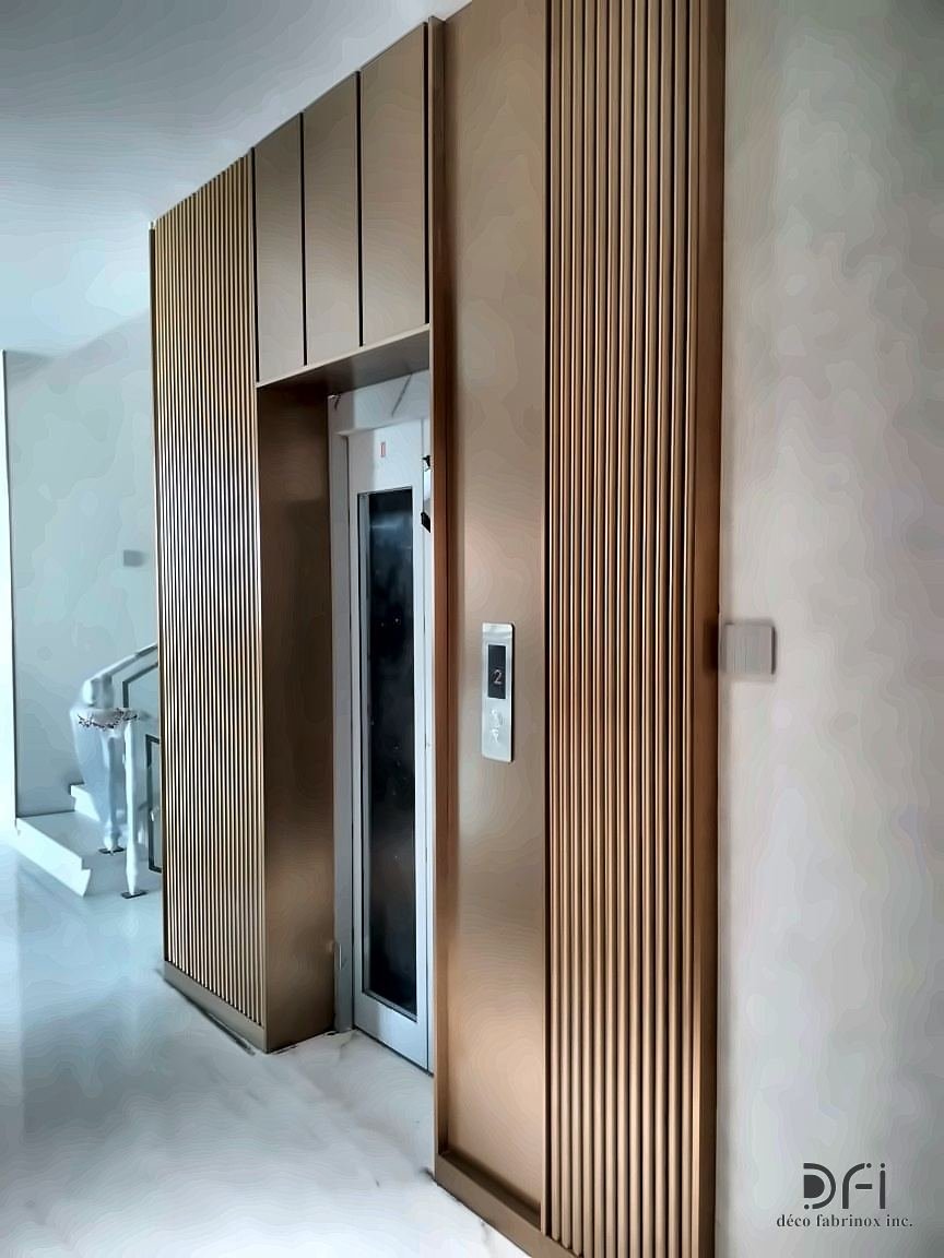 Lift entrance framed by a tall fluted bronze-toned metal surround