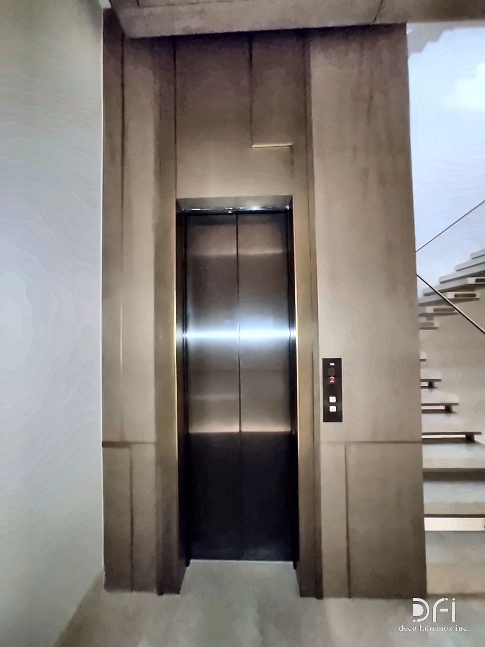 Lift entrance with a dark bronze-toned metal portal and frame