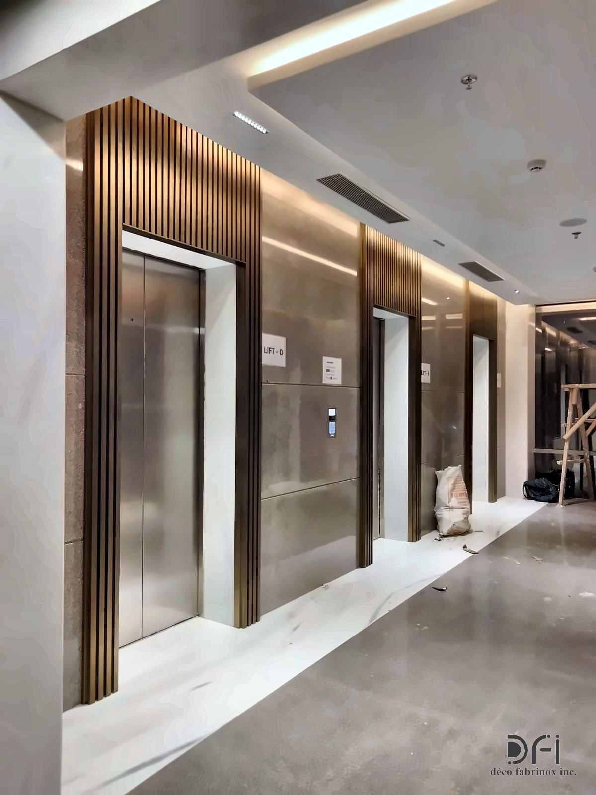 Lift lobby corridor lined with fluted bronze-toned metal surrounds