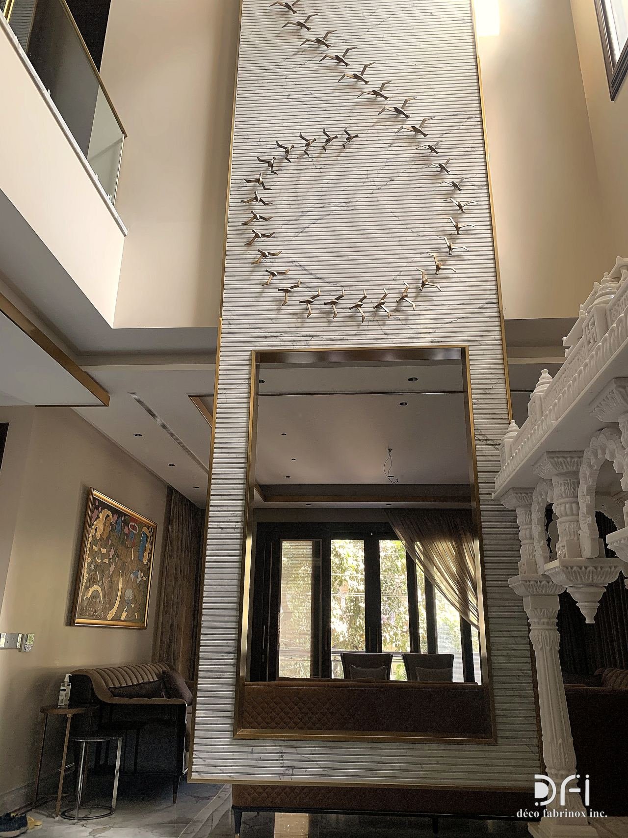Metal bird flock installation rising up a double-height stair hall