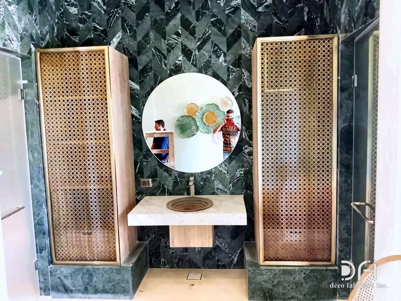 Perforated brass panels flanking a round mirror and basin
