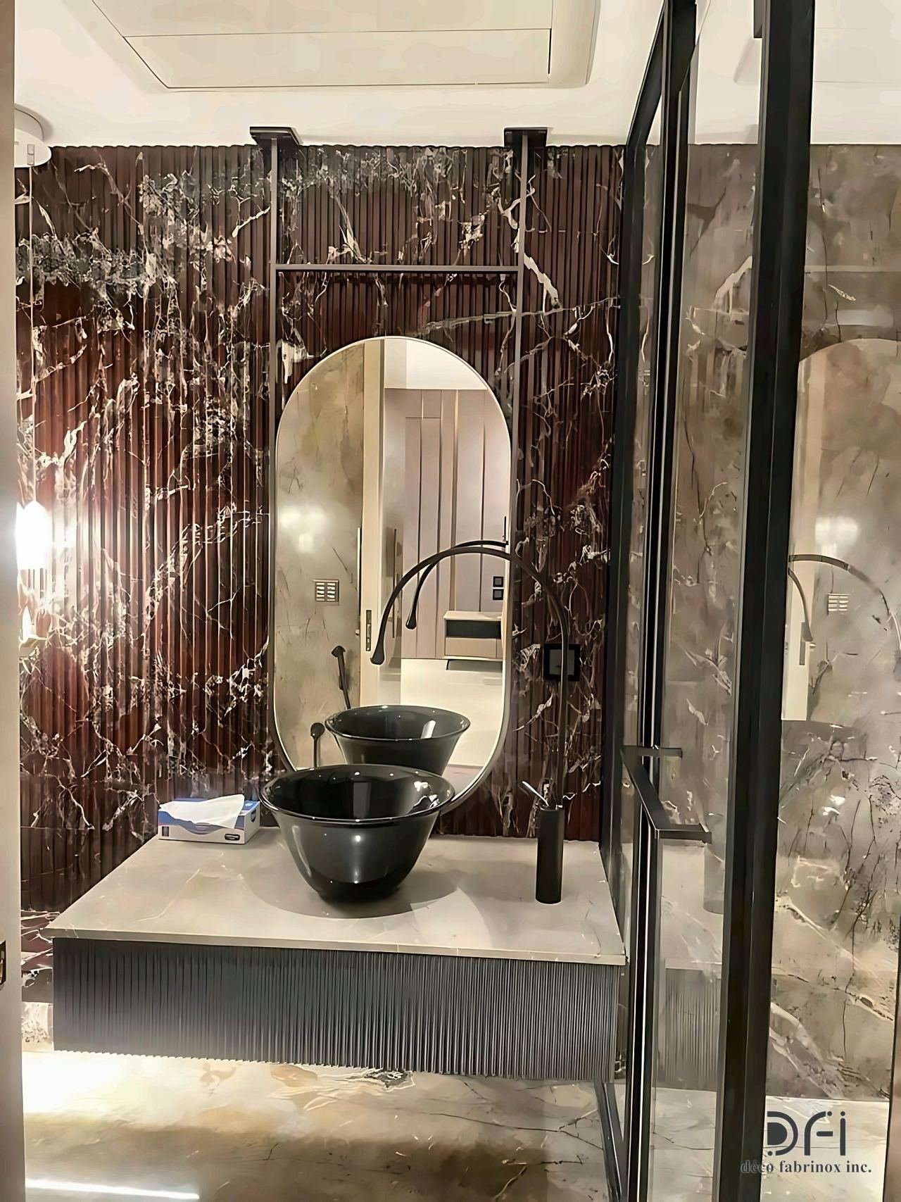 Arched brass mirror above a black stone basin