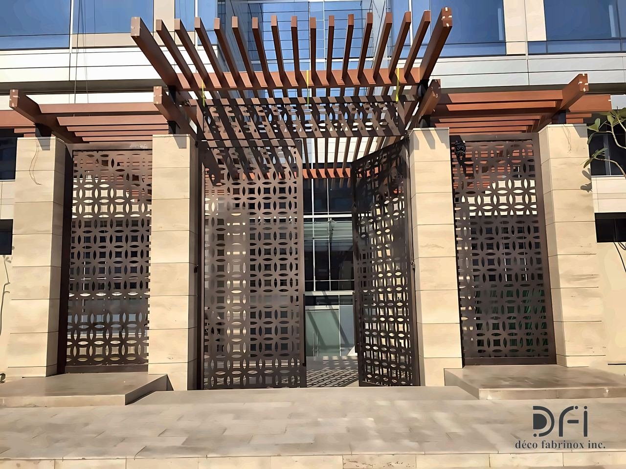 Laser-cut metal screens and gates under a slatted pergola at an entrance